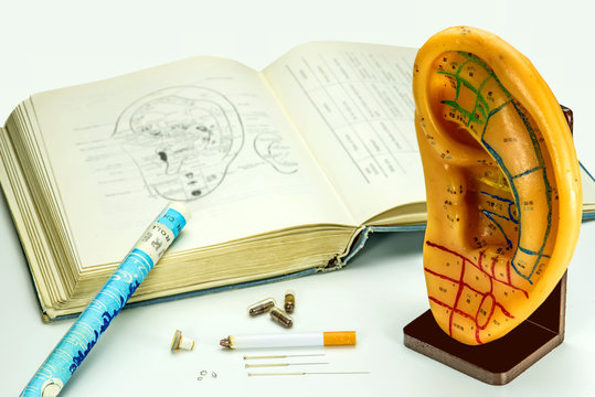 Ohrmodell mit Lehrbuch, Akupunkturnadeln und Moxazigarre