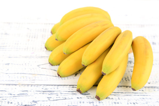 Bunch of mini bananas on color wooden background