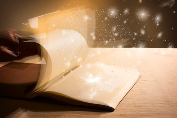 Hand leafing through a book with blank pages magic light.