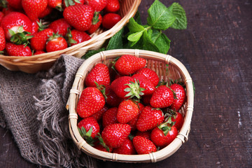 Ripe sweet strawberries in wicker basket and mint leaves