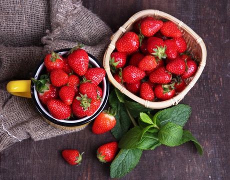 Ripe sweet strawberries in wicker basket and mint leaves