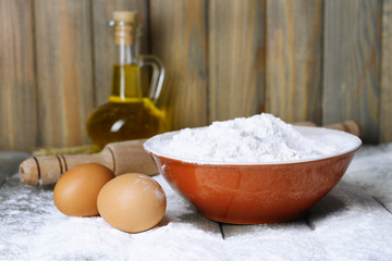 Flour in bowl on table on wooden background