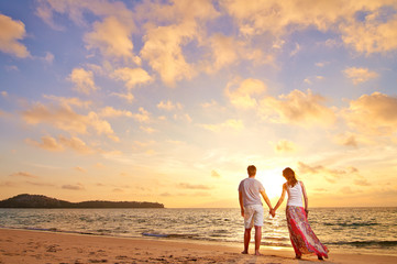 Fototapeta premium young couple stands at the sea beach looking at sunset