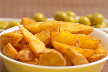 Fried potato wedges with olives on background