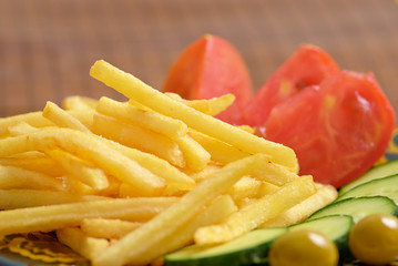 Close up of french fries with cucumber, tomato and olives