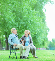 Mature couple talking seated on bench in park
