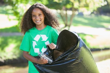 Young environmental activist smiling at the camera picking up tr