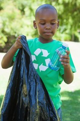 Little boy in recycling tshirt picking up trash