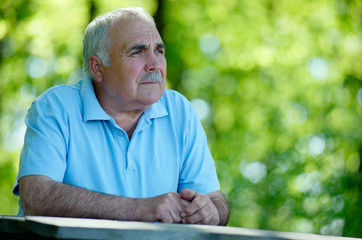 Elderly man sitting in the garden thinking