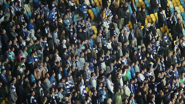 Fans in scarfs shout for playing team, stadium arena supporters
