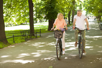 Mature couple relaxing by riding on the bike in park