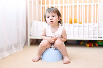 baby sitting on potty in home - obrazy, fototapety, plakaty