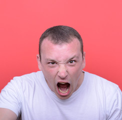 Portrait of angry man screaming against red background