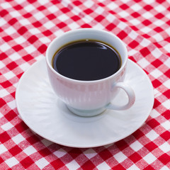 A cup of coffee on picnic blanket.