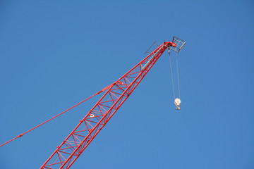 Red crane boom against a blue sky