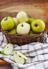 Fresh apples in basket on wooden table
