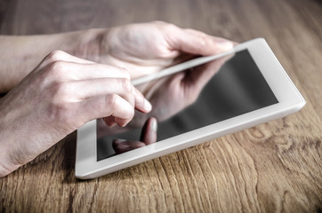White tablet with a blank screen in the hands on table