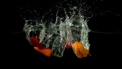 Chili peppers falling in water on black background - Powered by Adobe