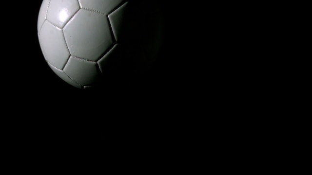 Football moving across black background