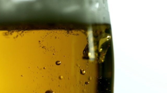 Glass of beer bubbling on white background