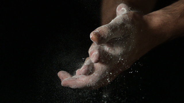 Bakers hands rubbing flour off on black background