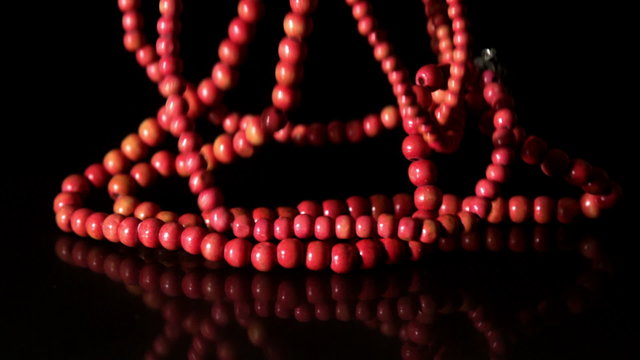 Red prayer beads falling on black background