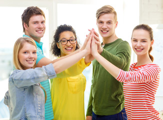 five smiling students giving high five at school