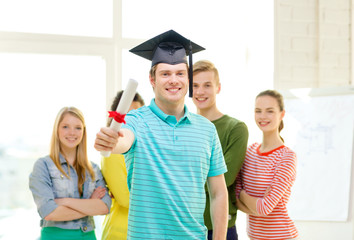 smiling male student with diploma and corner-cap