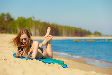 Summer vacation Girl with phone tanning on beach
