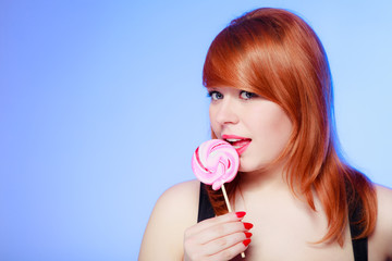 Sexy woman holding candy. Redhair girl eating sweet lollipop