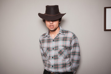 Young cowboy in plaid shirt against a green wall
