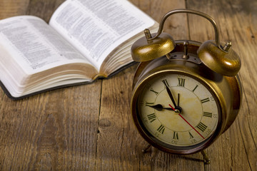 Bible with clock on wood