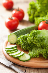 fresh cucumber tomatoes and salad leaves on chopping board