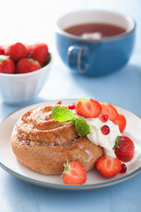sweet cinnamon roll with cream and strawberry for breakfast