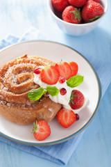 sweet cinnamon roll with cream and strawberry for breakfast