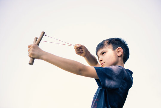 Child aiming with sling outdoors portrait.