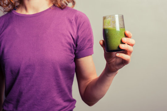 Young woman holding a glass of green smoothie