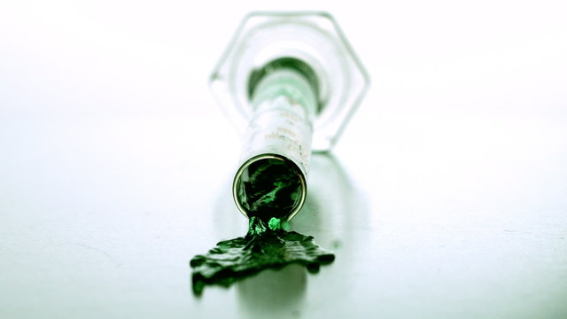 Graduated cylinder falling and spilling green liquid