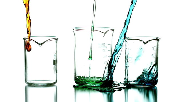 Liquid pouring into beakers on white background