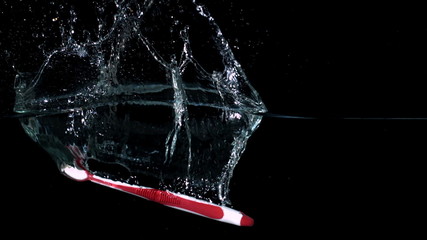 Pink toothbrush falling in water on black background - Powered by Adobe