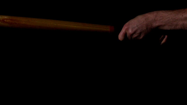 Man hitting baseball with bat on black background