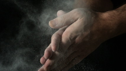 Bakers hands clapping flour off on black background