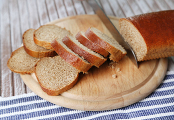 Female hands cutting bread on wooden board, close-up
