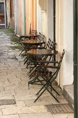 Cafe with metal chairs and tables on a stone street
