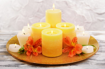 Fototapeta na wymiar Beautiful candles with flowers on table on grey background