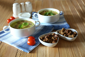 Tasty soup in saucepans on wooden table, close up