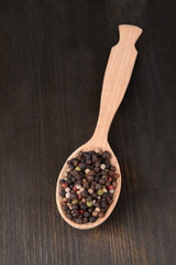 Spice pepper in spoon on wooden background