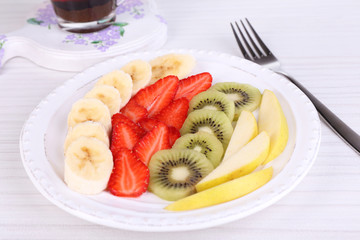 Various sliced fruits on plate on table close-up