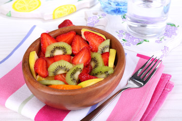 Various sliced fruits in bowl on table close-up