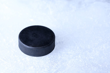 Black hockey puck on ice rink background